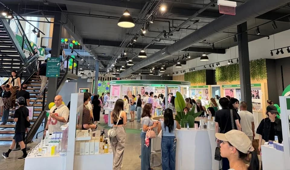 Interior of the Lotte Homeshopping Eeseol pop-up store in Los Angeles with visitors browsing K-Beauty brand booths